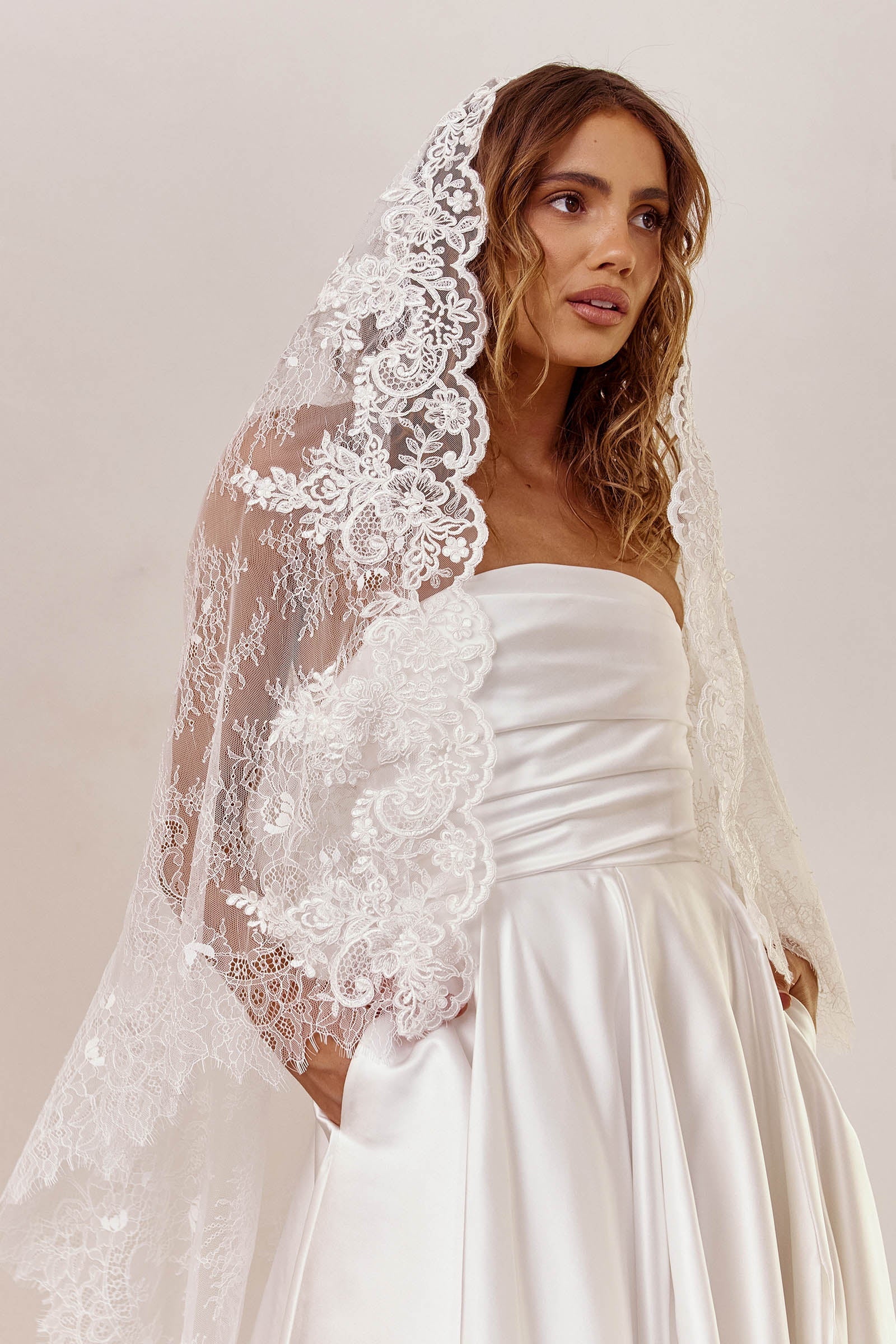 Woman wearing a strapless wedding dress with a lace veil_XS_