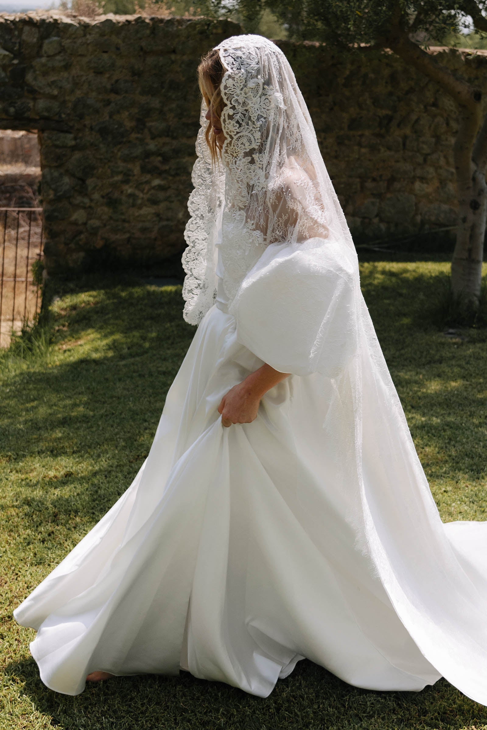 Woman wearing a satin wedding dress and lace mantilla veil_XS_
