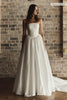 A woman wearing a strapless white wedding gown with a structured bodice and full skirt
