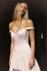 A woman wearing an off-the-shoulder white wedding dress with a fitted bodice and flowing skirt_XS_