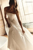 A woman wearing a strapless white wedding gown with a fitted bodice and flowing skirt