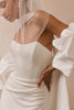 A close-up of a model wearing a white wedding dress with a structured sweetheart neckline, dramatic puffed sleeves, and a sheer veil.
