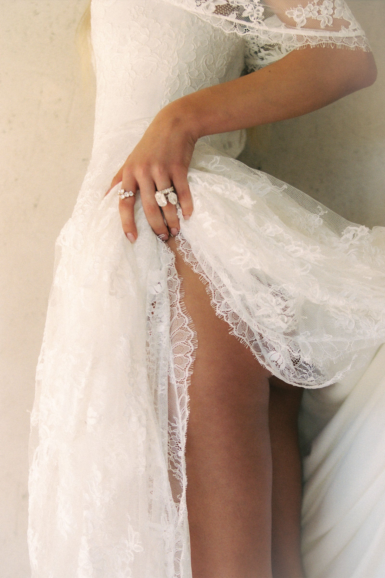 A woman wearing a white off-the-shoulder lace wedding gown with a deep V neckline and a full layered skirt_XS_