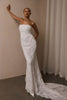 A woman wearing a strapless white lace wedding gown with a long train