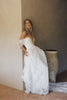 A woman wearing a white off-the-shoulder lace wedding gown with a deep V neckline and a full layered skirt_XS_