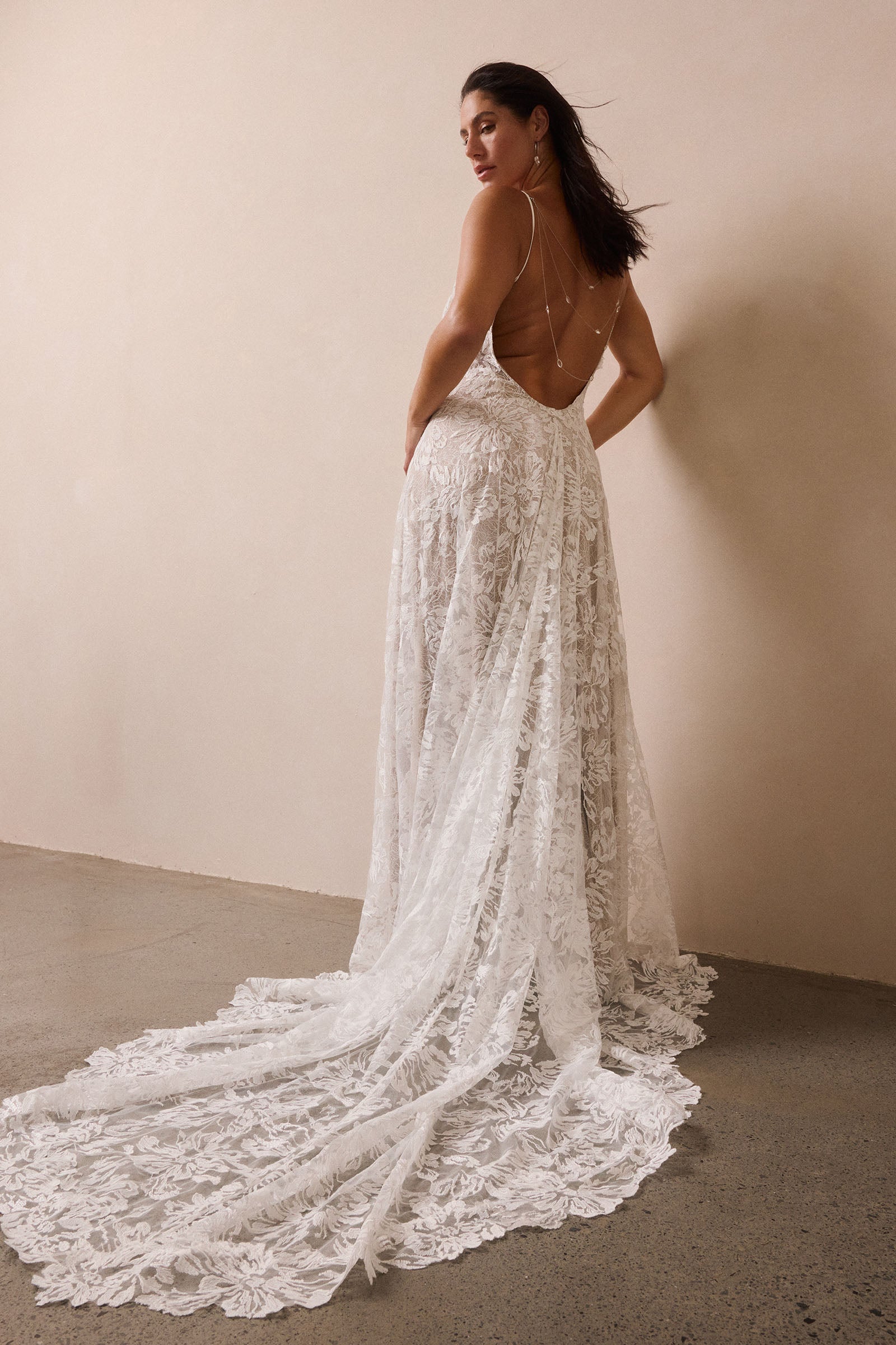 woman wearing a white lace backless dress with thin straps and delicate chain jewellery across her back_L_