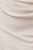 A close-up of draped cream-colored fabric with soft folds and a smooth texture.