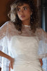 Woman wearing a white lace dress with lace cape and pearl drop earrings