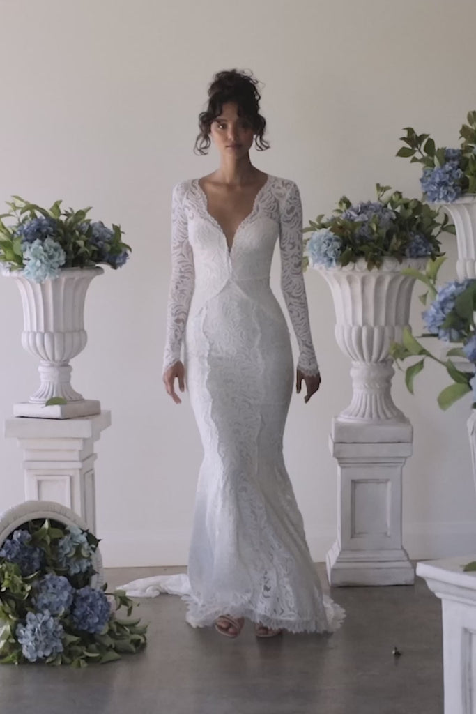 A woman in a long sleeve lace wedding dress.