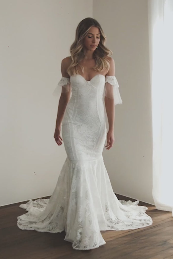 A woman walking in a strapless lace wedding dress.